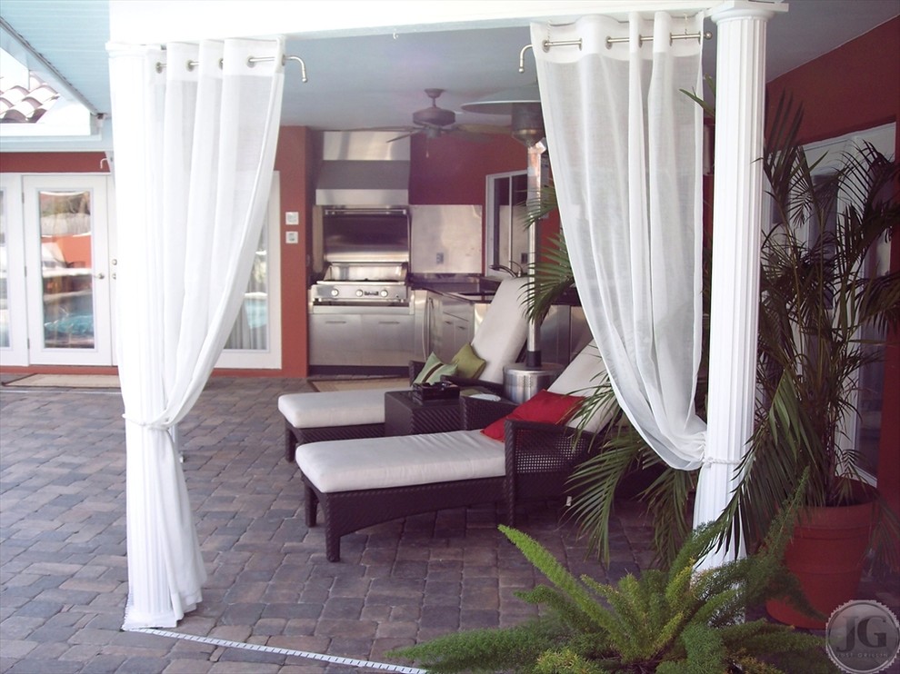 Idee per un grande patio o portico contemporaneo dietro casa con pavimentazioni in mattoni e un parasole