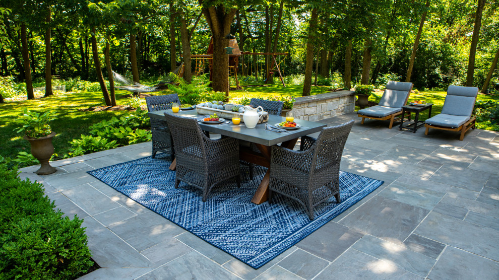 Ejemplo de patio tradicional grande sin cubierta en patio trasero con chimenea y adoquines de piedra natural