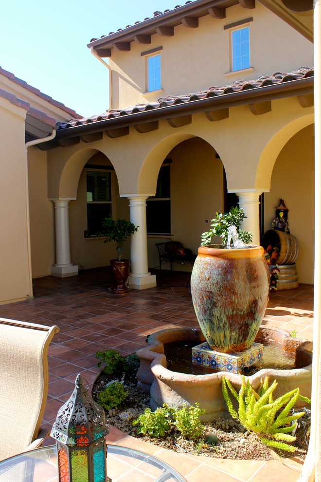 Источник вдохновения для домашнего уюта: двор в средиземноморском стиле с фонтаном и покрытием из плитки без защиты от солнца