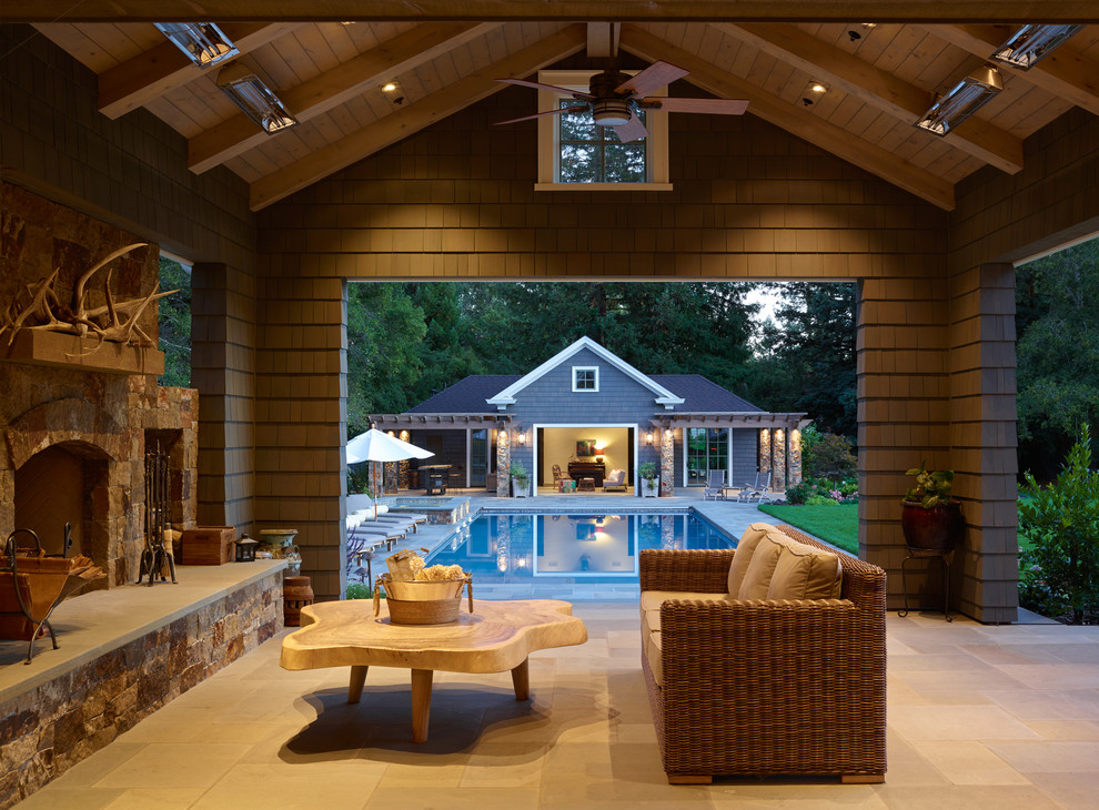 Immagine di un grande patio o portico chic dietro casa con piastrelle, un tetto a sbalzo e un caminetto