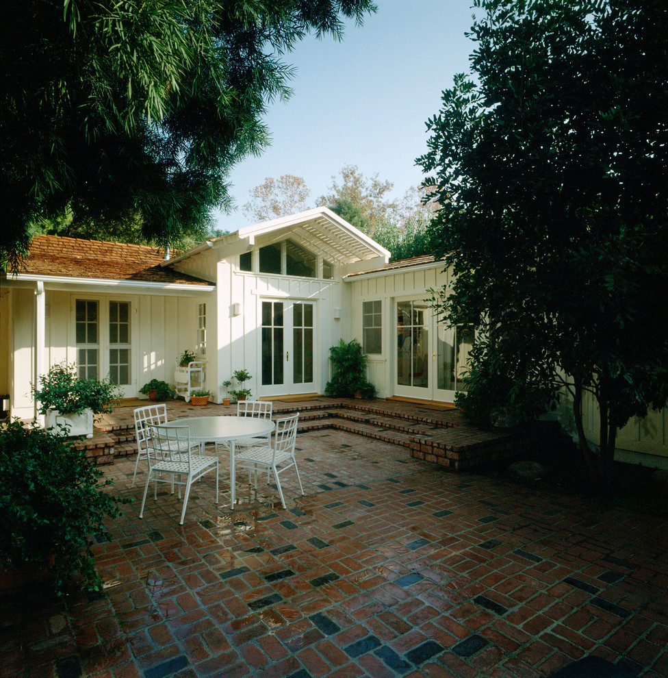 Exemple d'une terrasse arrière tendance de taille moyenne avec des pavés en brique et une extension de toiture.