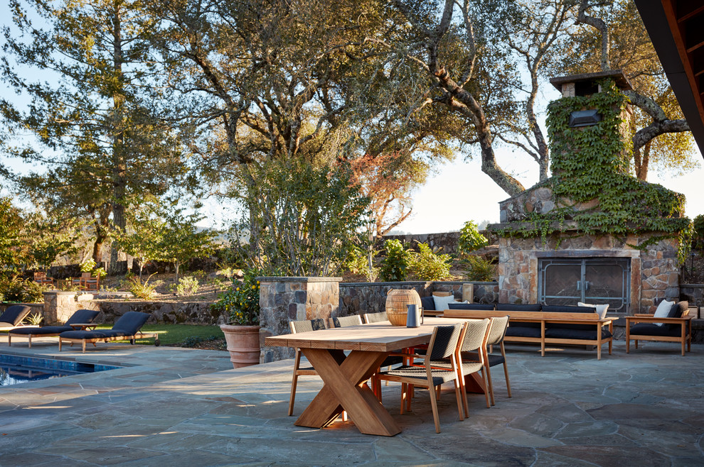 Modelo de patio campestre sin cubierta en patio trasero con chimenea y suelo de baldosas