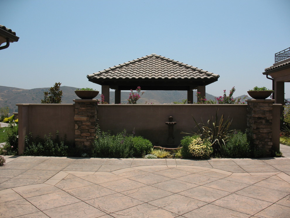 Large tuscan backyard stamped concrete patio photo in Los Angeles with a pergola