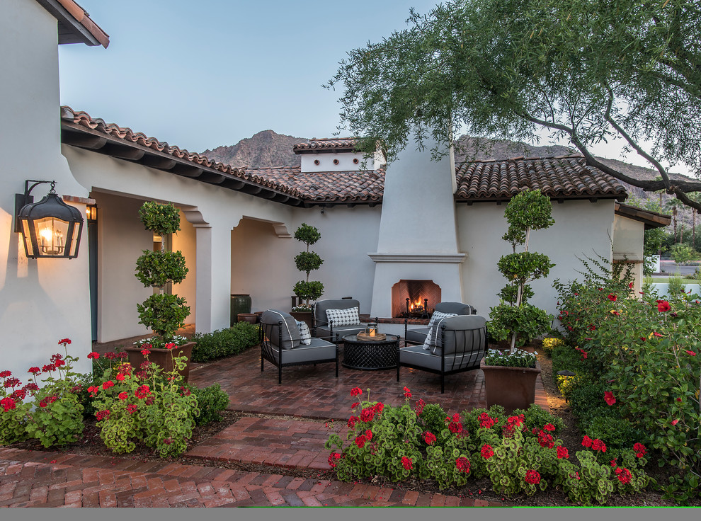 Example of a mid-sized tuscan brick patio design in Phoenix with a fire pit and no cover