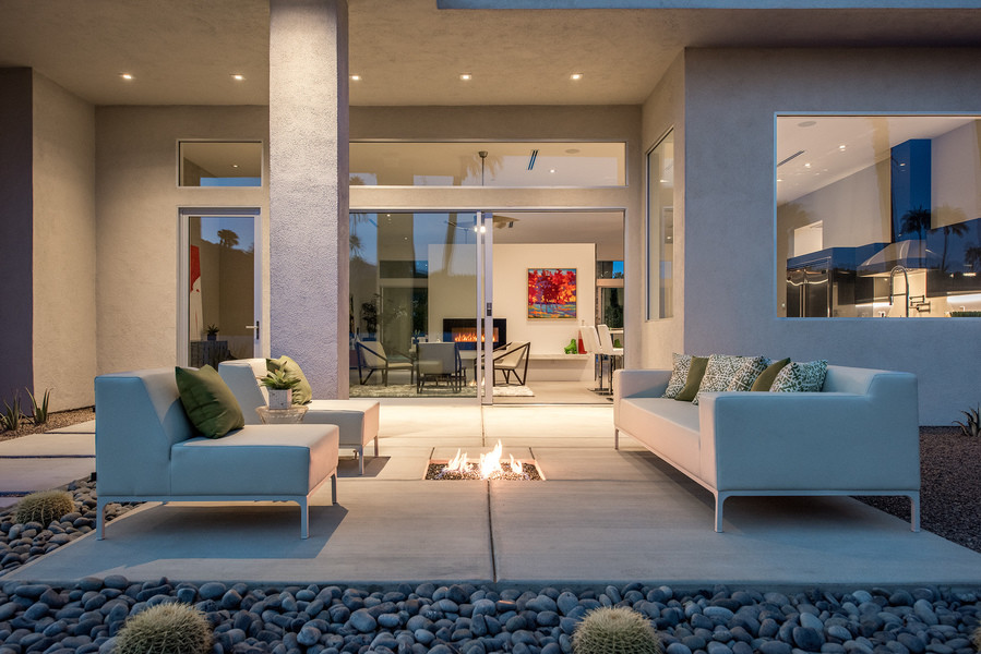 This is an example of an expansive contemporary front patio in Other with a fire feature, concrete slabs and no cover.