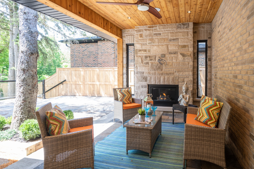 Imagen de patio contemporáneo de tamaño medio en patio trasero y anexo de casas con chimenea y adoquines de piedra natural