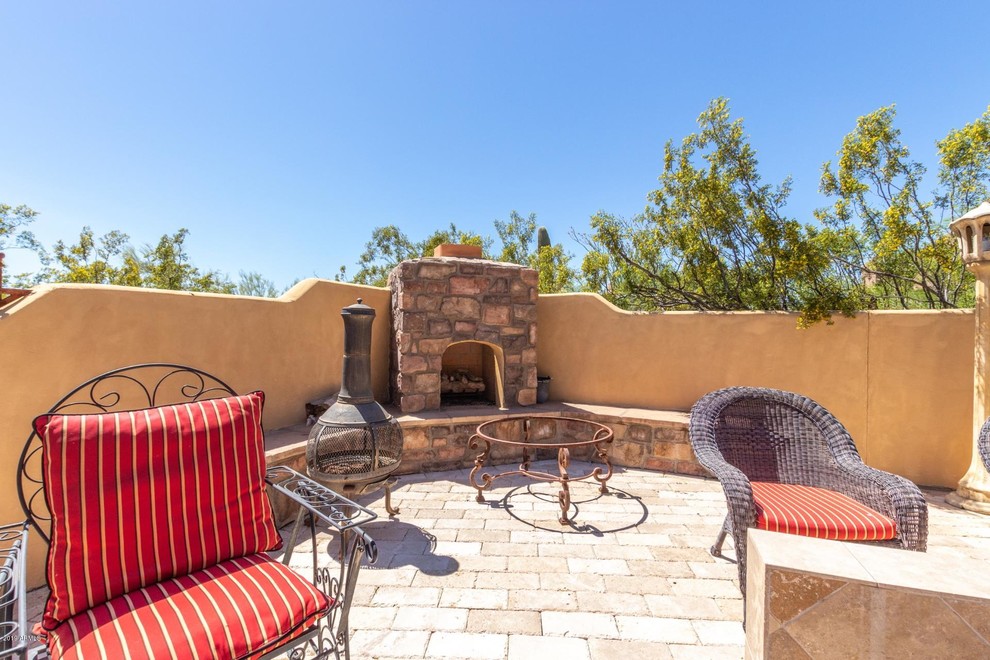 Design ideas for a mid-sized mediterranean backyard patio in Phoenix with with fireplace, brick pavers and no cover.