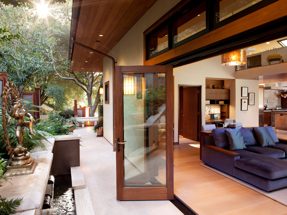 Idée de décoration pour une terrasse arrière asiatique de taille moyenne avec des pavés en pierre naturelle et une extension de toiture.