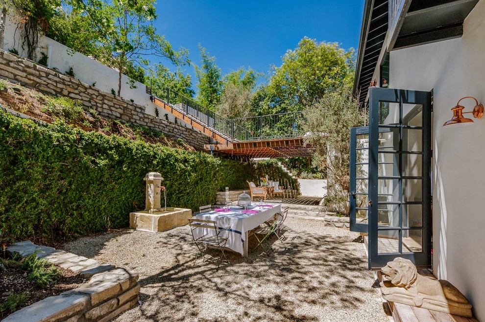 Ejemplo de patio mediterráneo grande sin cubierta en patio trasero con fuente y gravilla