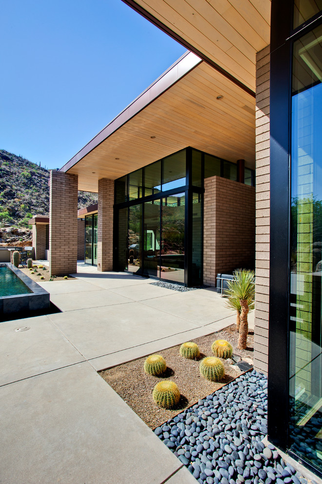 Example of a mid-sized minimalist backyard concrete patio design in Phoenix with a roof extension