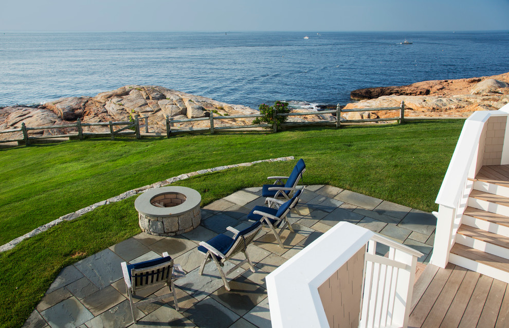 Example of a mid-sized beach style backyard stone patio design in Boston with a fire pit