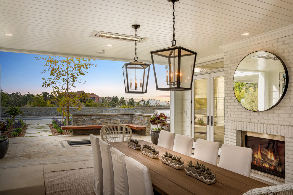 Photo of a coastal back patio in Los Angeles with a roof extension and a fireplace.