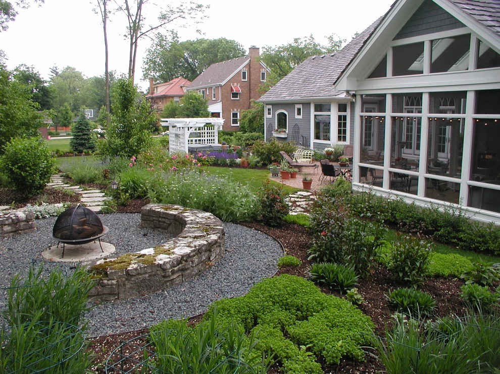 Modelo de patio clásico grande en patio trasero con gravilla, pérgola y brasero