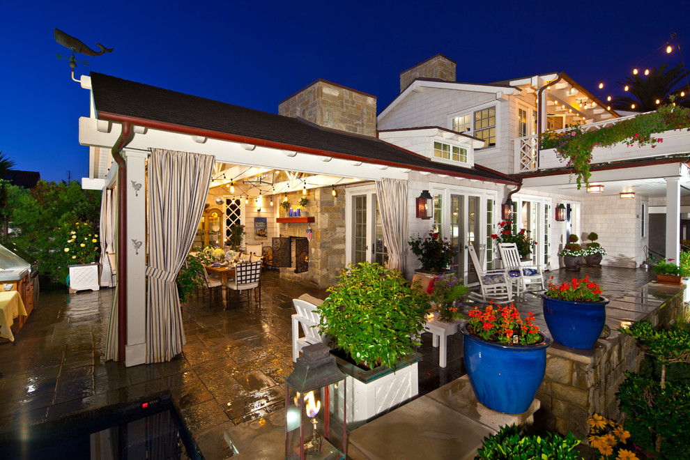 Immagine di un patio o portico stile marino dietro casa con pavimentazioni in pietra naturale e un tetto a sbalzo