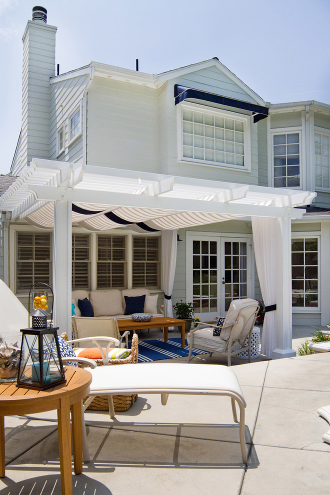 Idee per un grande patio o portico stile marino dietro casa con cemento stampato e una pergola