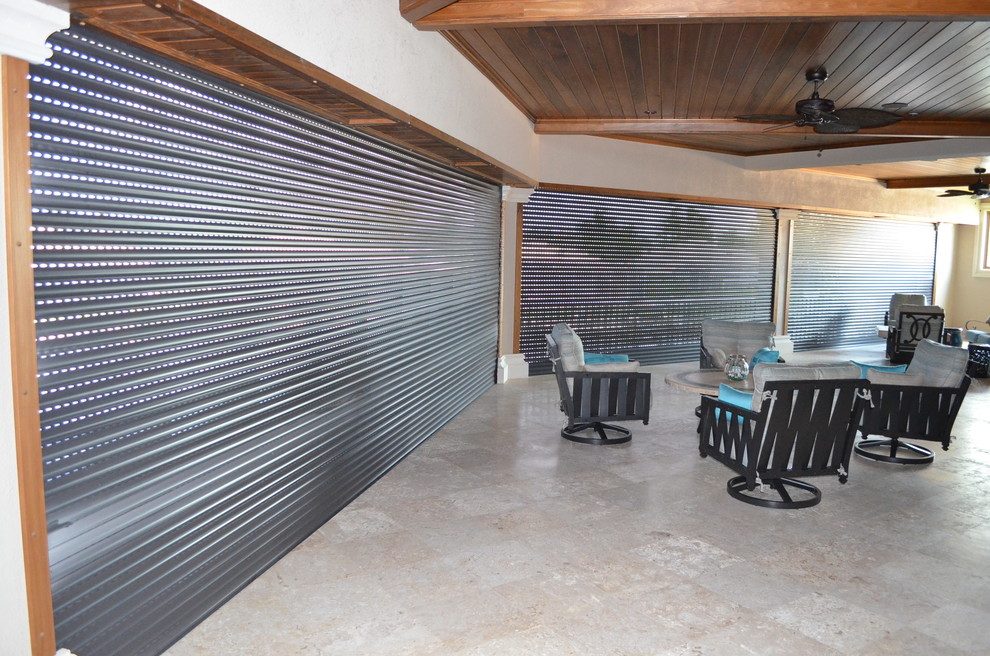 Foto di un grande patio o portico tropicale dietro casa con piastrelle e un tetto a sbalzo