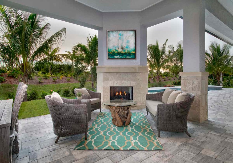 Inspiration for a large coastal back patio in Miami with a roof extension, natural stone paving and a fireplace.