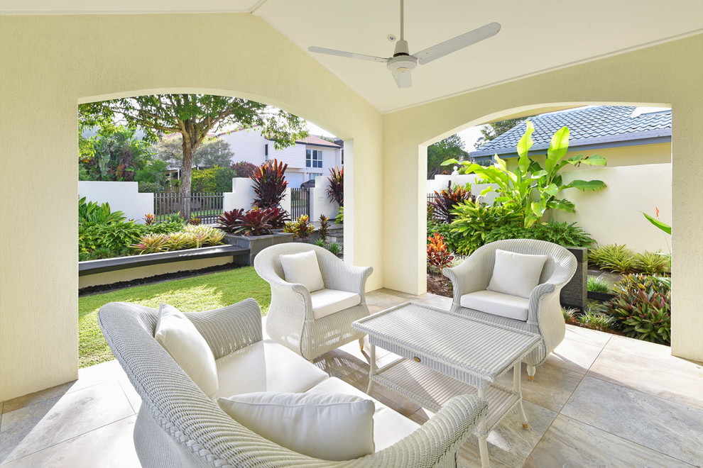 Foto di un patio o portico tropicale dietro casa con piastrelle e un tetto a sbalzo