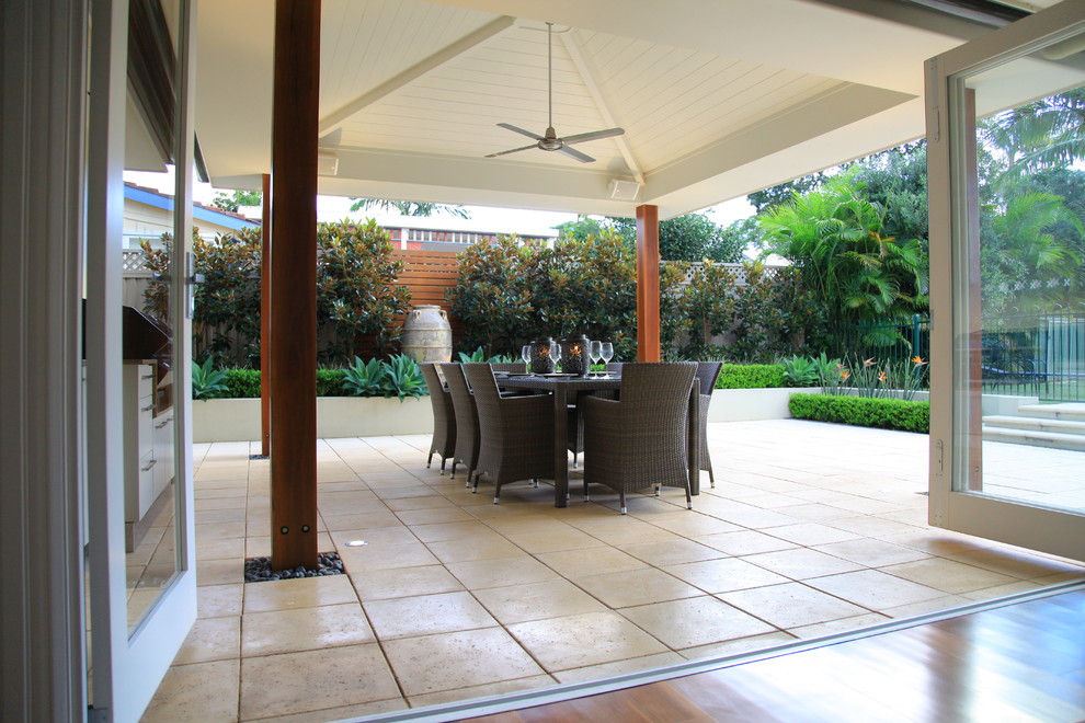 Modelo de patio actual de tamaño medio en patio lateral con cocina exterior, adoquines de hormigón y toldo