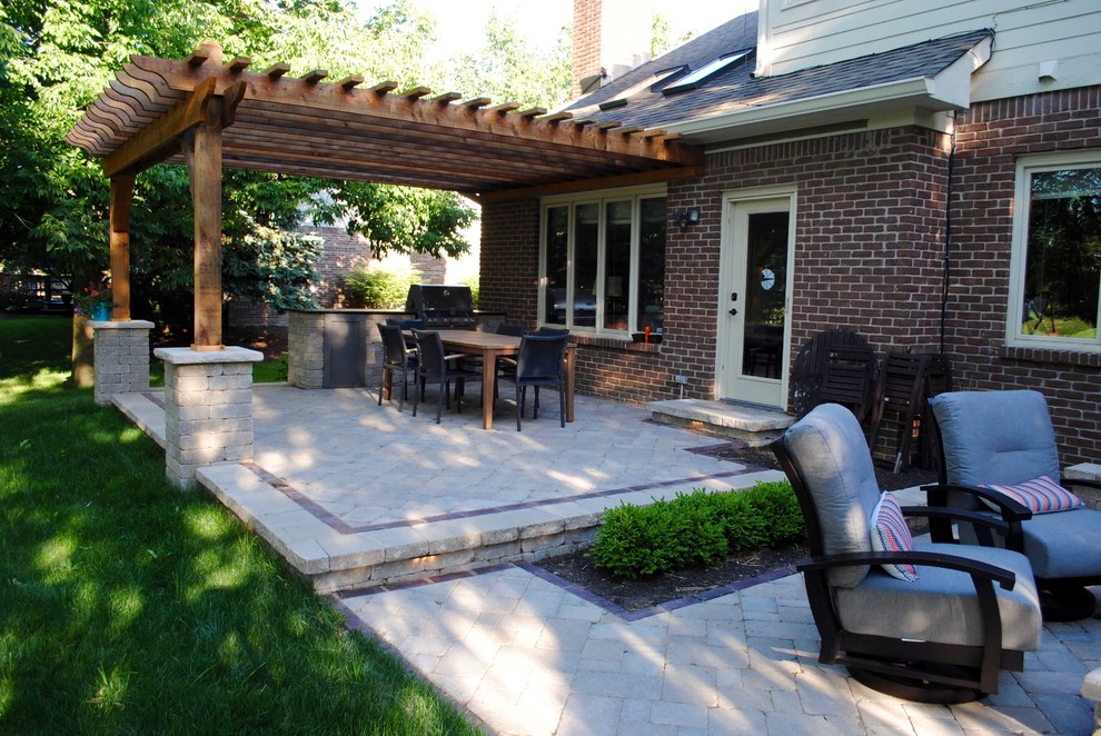 Cette photo montre une terrasse arrière chic avec une cuisine d'été, des pavés en béton et une pergola.