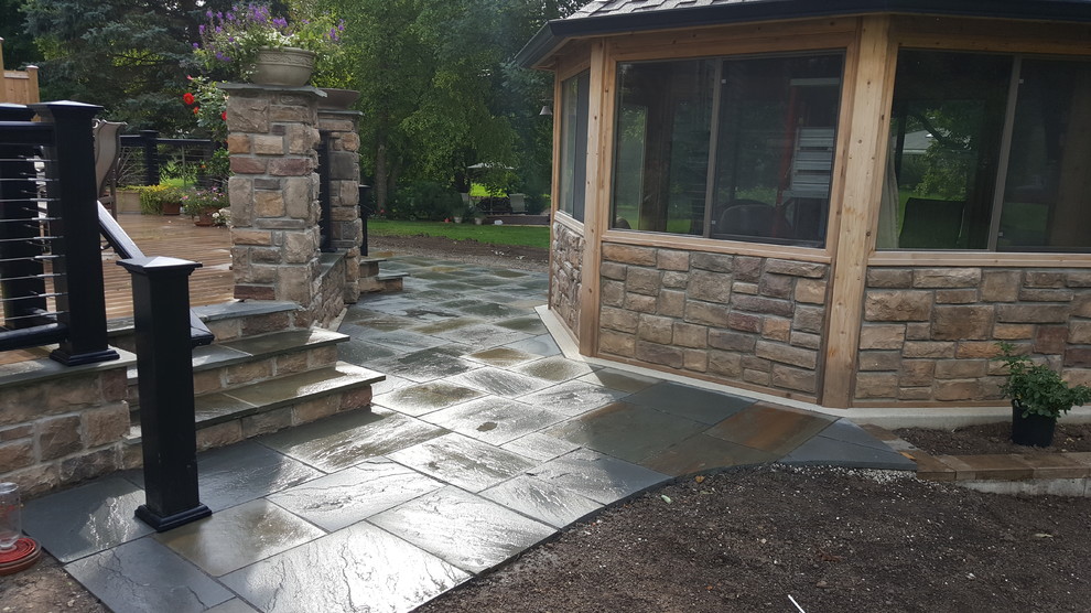 Example of a mid-sized transitional backyard stone patio design in Chicago with a gazebo