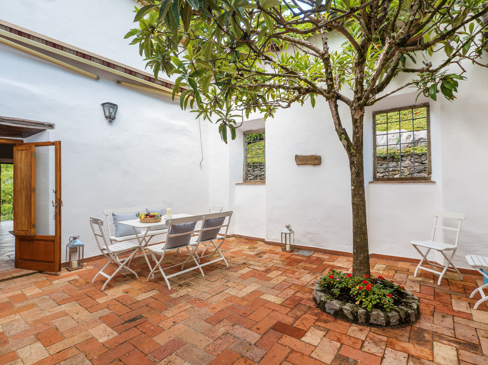 Foto di un patio o portico mediterraneo di medie dimensioni e dietro casa con un giardino in vaso, pavimentazioni in mattoni e nessuna copertura