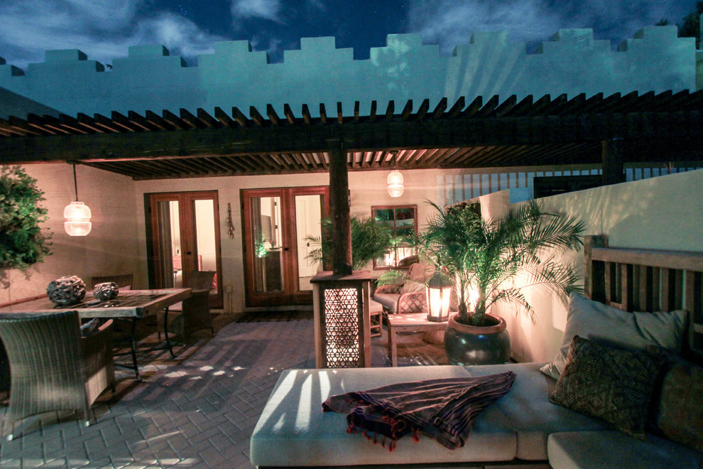 Immagine di un patio o portico eclettico di medie dimensioni e in cortile con pavimentazioni in mattoni e un tetto a sbalzo