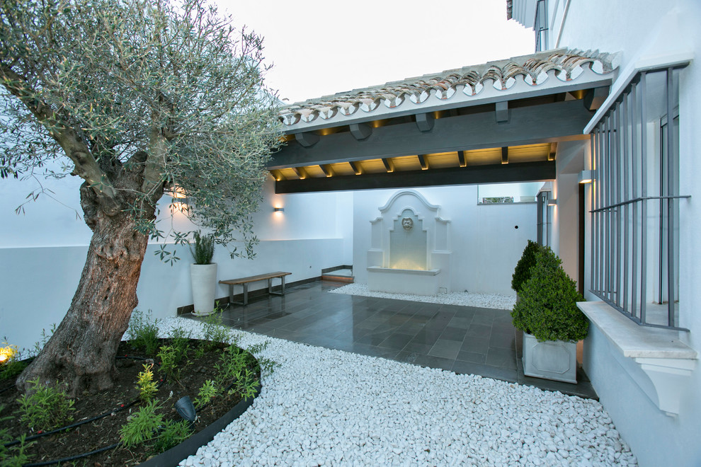 Idée de décoration pour une terrasse méditerranéenne de taille moyenne avec un point d'eau, une extension de toiture, une cour et du gravier.