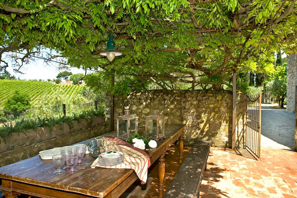 Immagine di un patio o portico country davanti casa con pavimentazioni in mattoni e una pergola