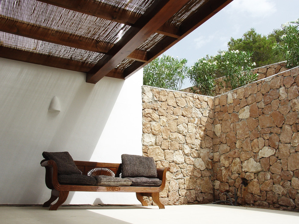 Immagine di un patio o portico mediterraneo di medie dimensioni e dietro casa con lastre di cemento