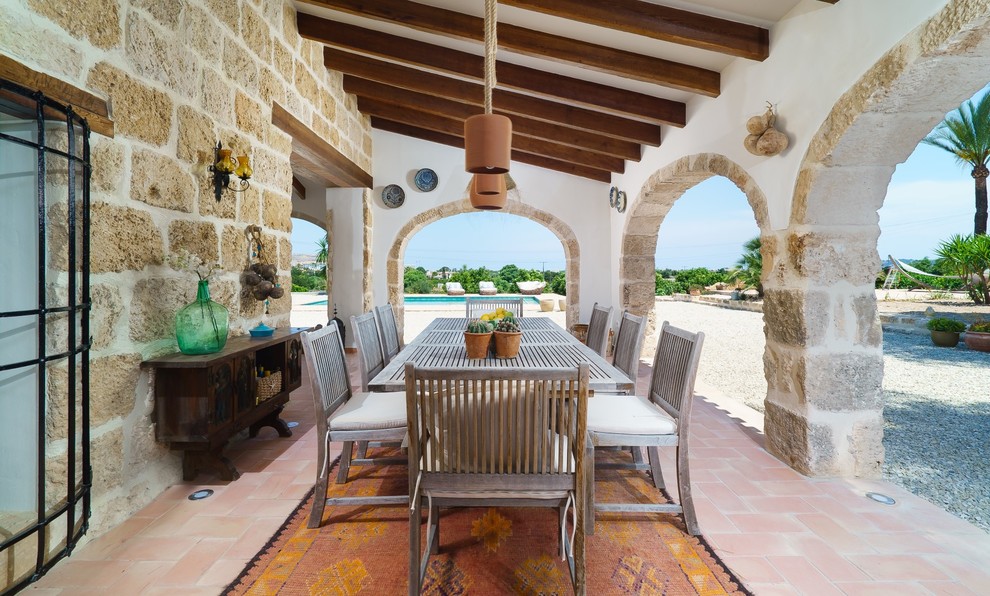 Пример оригинального дизайна: двор на боковом дворе в средиземноморском стиле с покрытием из плитки и навесом