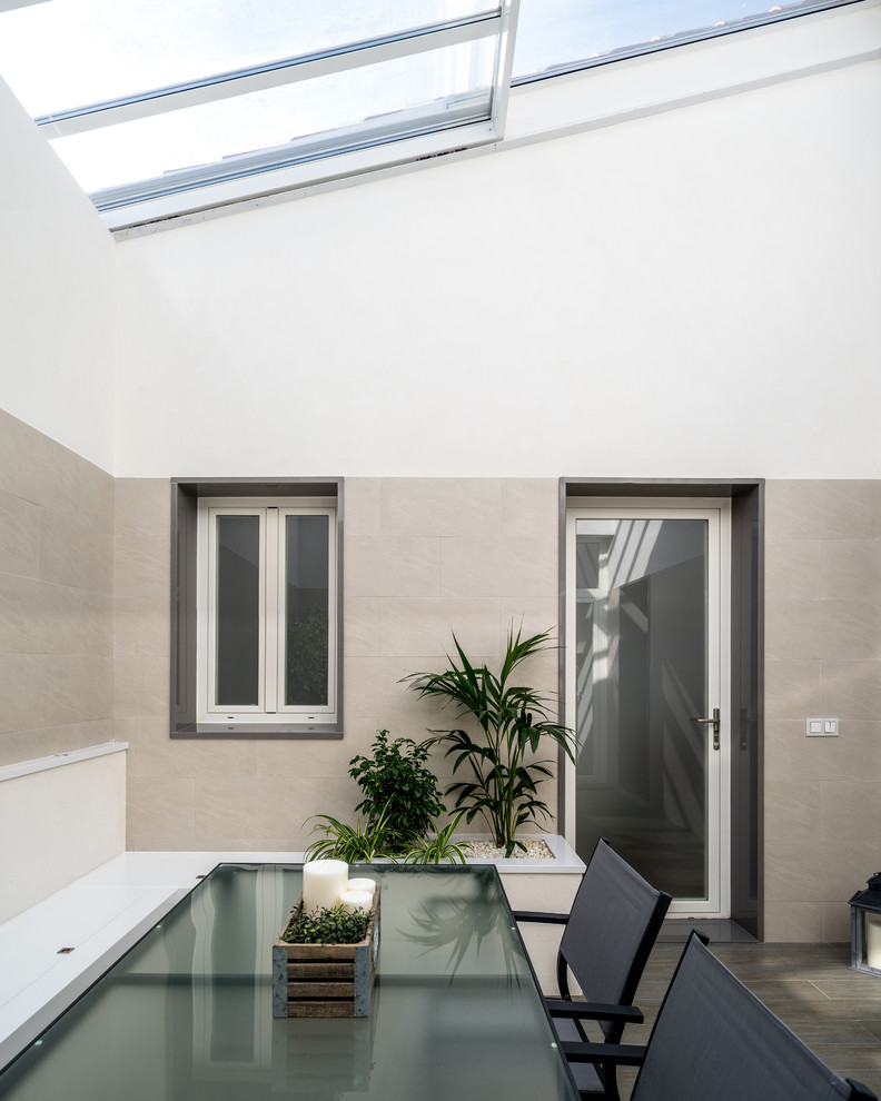 Inspiration for a medium sized contemporary back patio in Seville with a potted garden, tiled flooring and a roof extension.