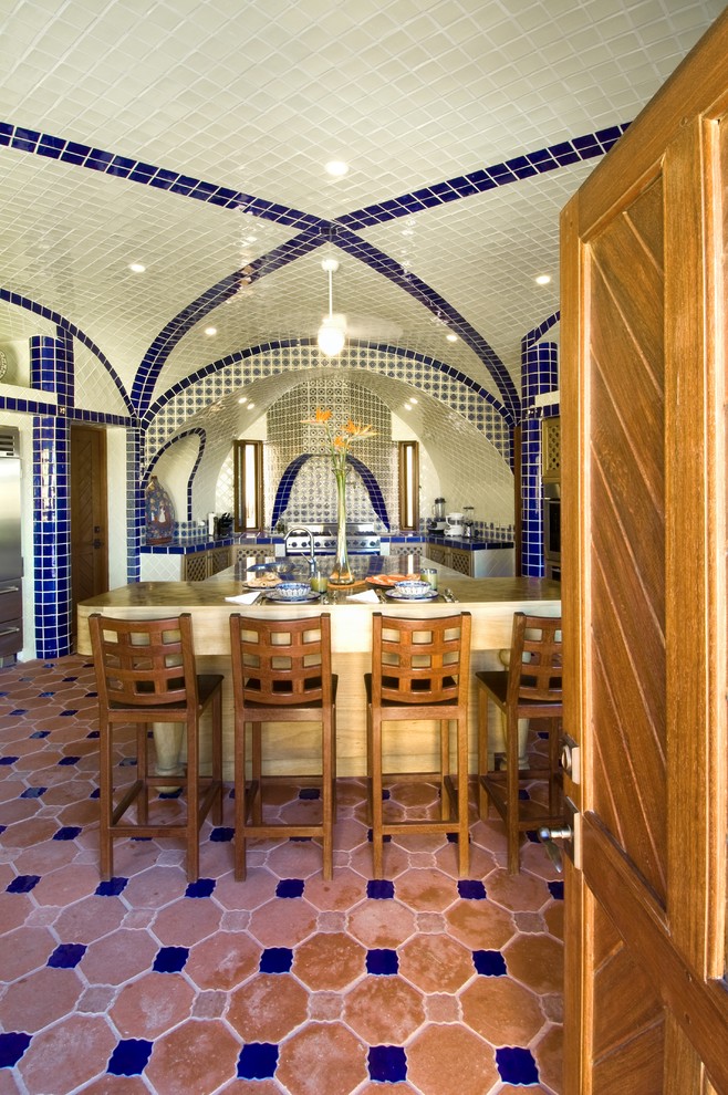 Cette image montre une terrasse méditerranéenne avec une cuisine d'été, du carrelage et une extension de toiture.