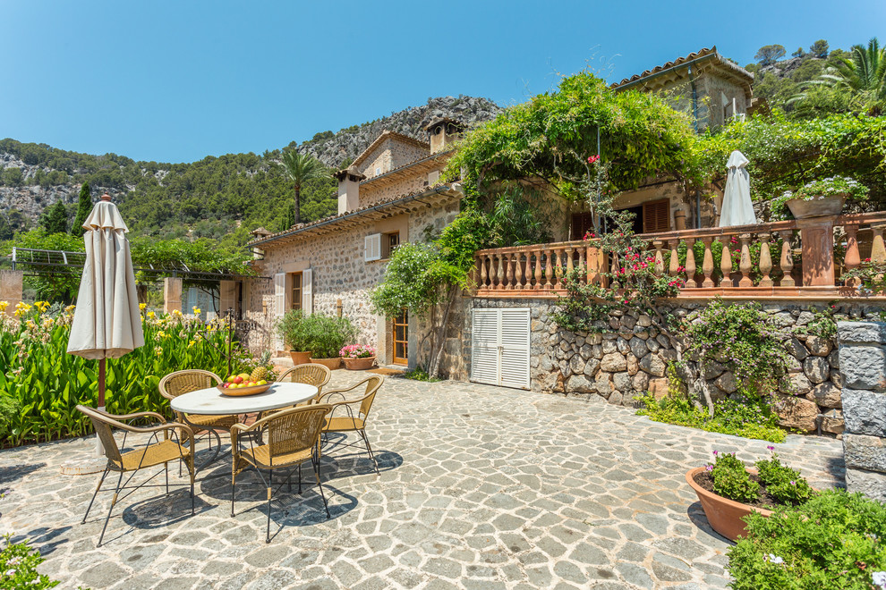 Réalisation d'une terrasse avant méditerranéenne avec aucune couverture et des pavés en pierre naturelle.