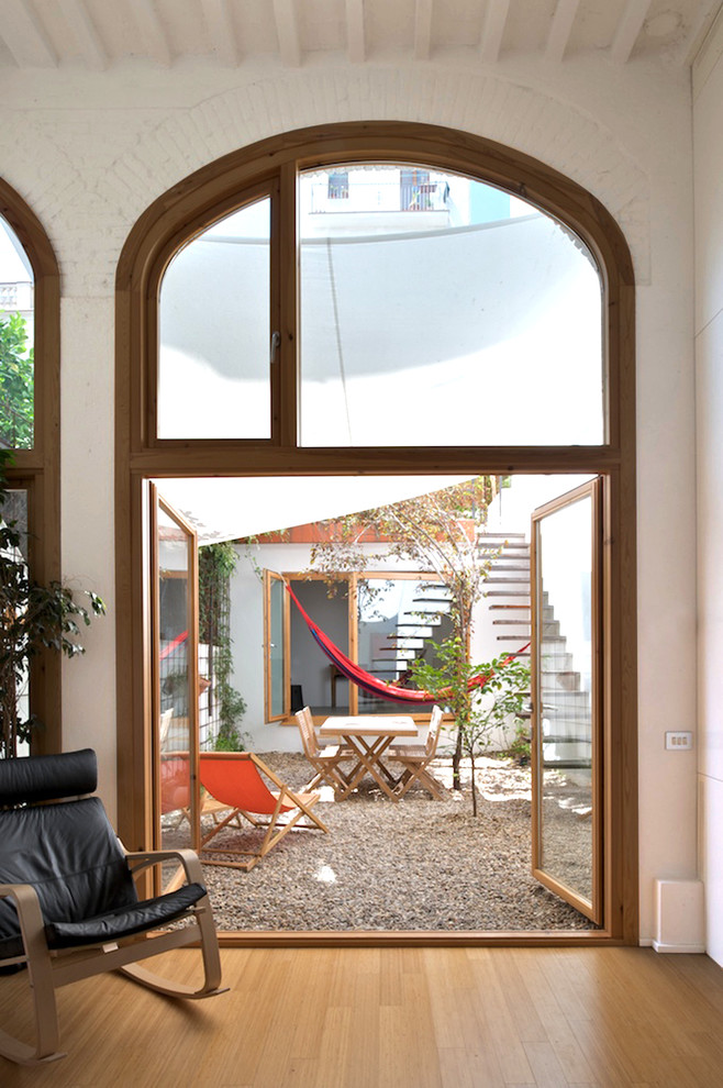 На фото: двор среднего размера на внутреннем дворе с покрытием из гравия и козырьком