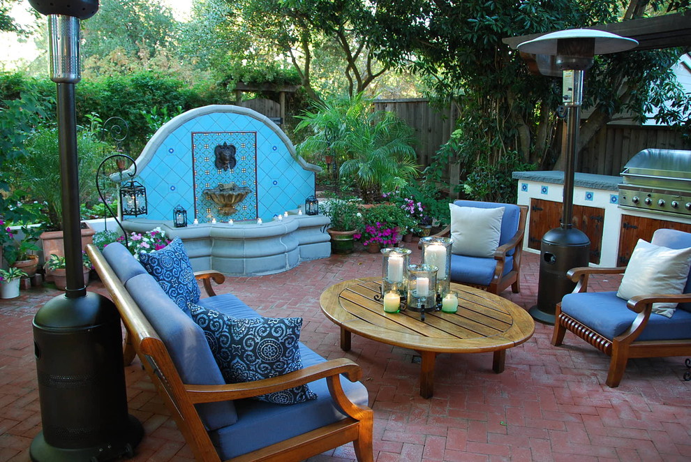 Diseño de patio mediterráneo grande en patio trasero con adoquines de ladrillo, cocina exterior y pérgola