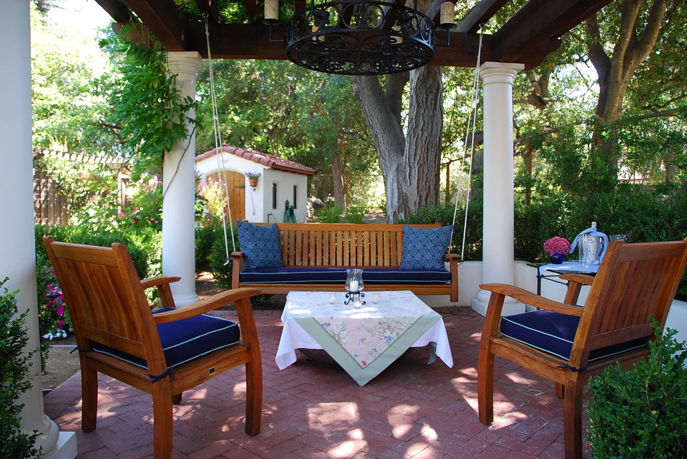 Ejemplo de patio mediterráneo grande en patio trasero con adoquines de ladrillo y cenador