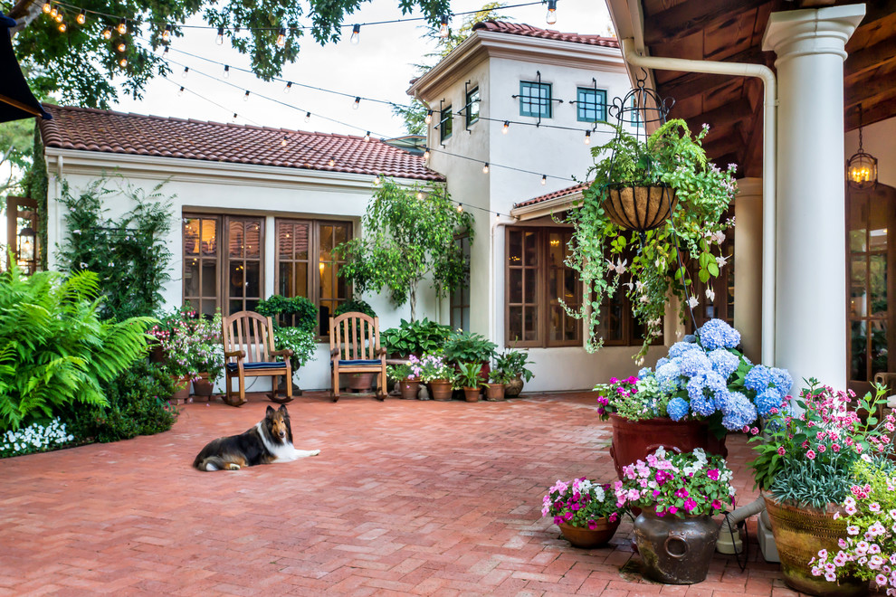 На фото: большой двор на внутреннем дворе в средиземноморском стиле с мощением клинкерной брусчаткой с