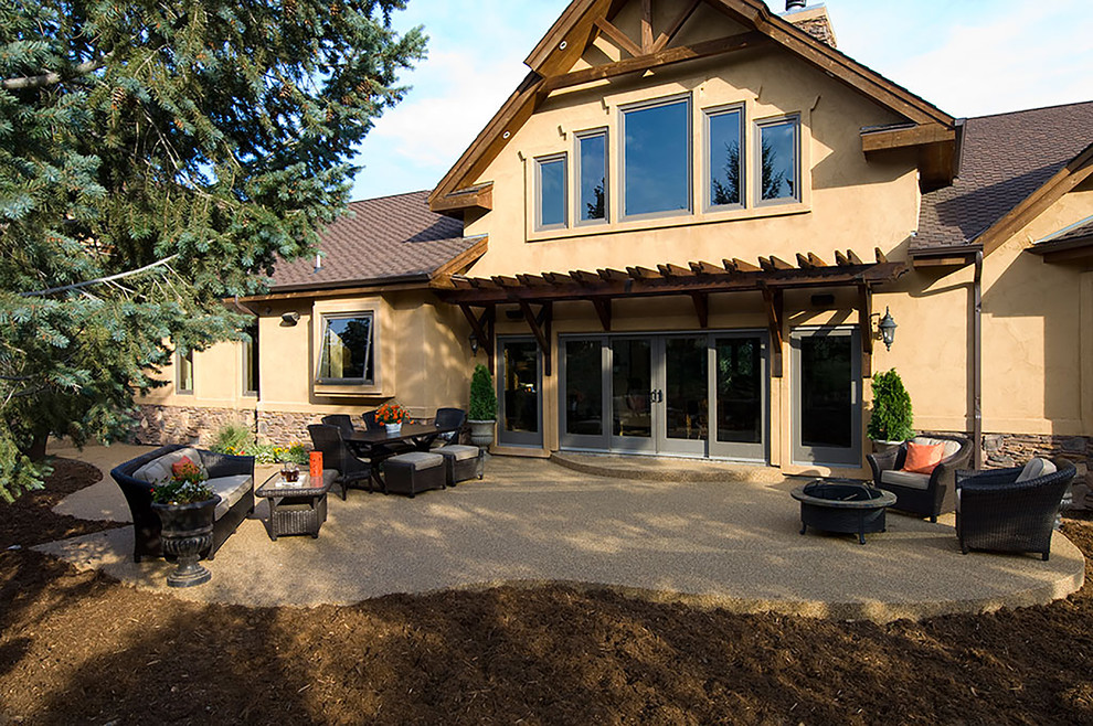 Idée de décoration pour une très grande terrasse arrière chalet avec un foyer extérieur, du béton estampé et une pergola.