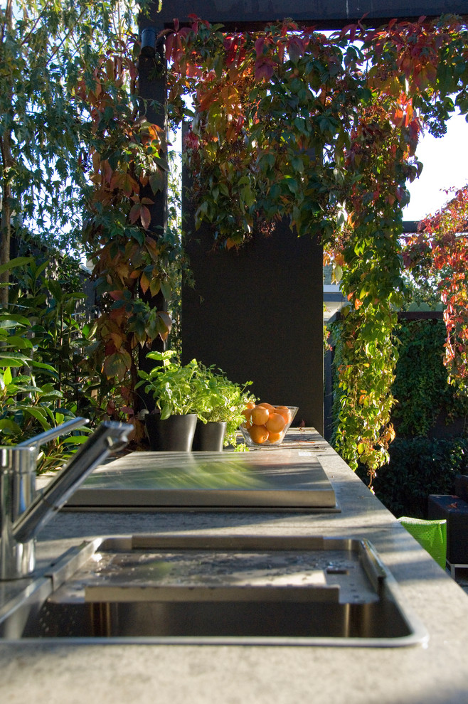 Idées déco pour une terrasse arrière contemporaine de taille moyenne avec une cuisine d'été, des pavés en pierre naturelle et une pergola.