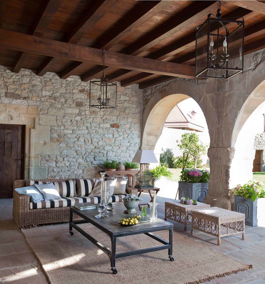 Esempio di un patio o portico mediterraneo con pavimentazioni in pietra naturale e un tetto a sbalzo