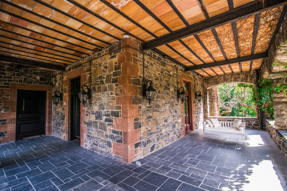 Immagine di un patio o portico vittoriano di medie dimensioni e dietro casa con pavimentazioni in pietra naturale e un tetto a sbalzo