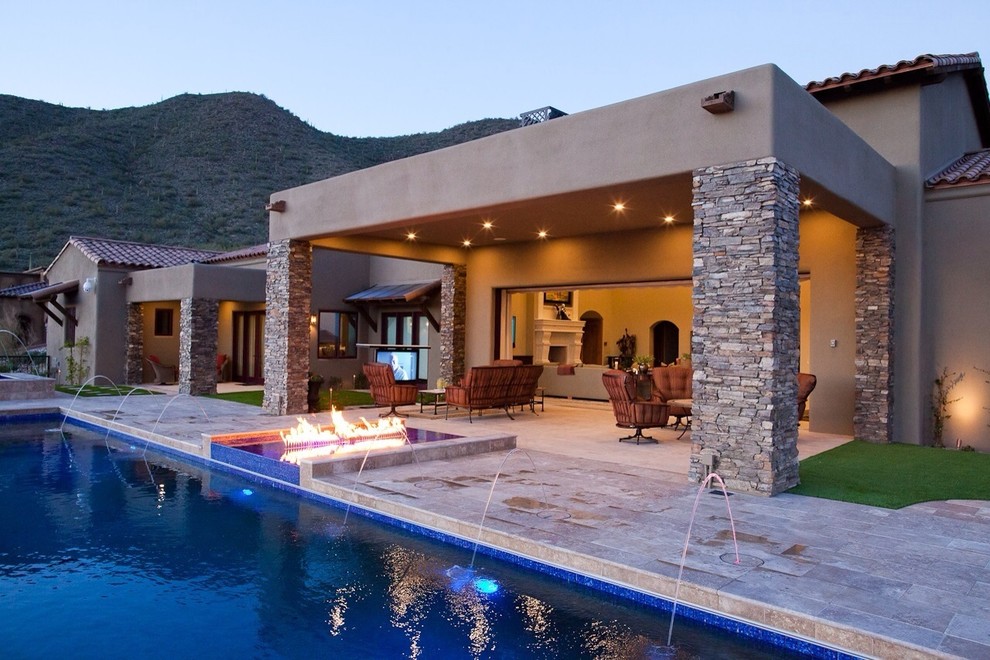 Example of a large trendy backyard stone patio design in Phoenix with a fire pit and a roof extension