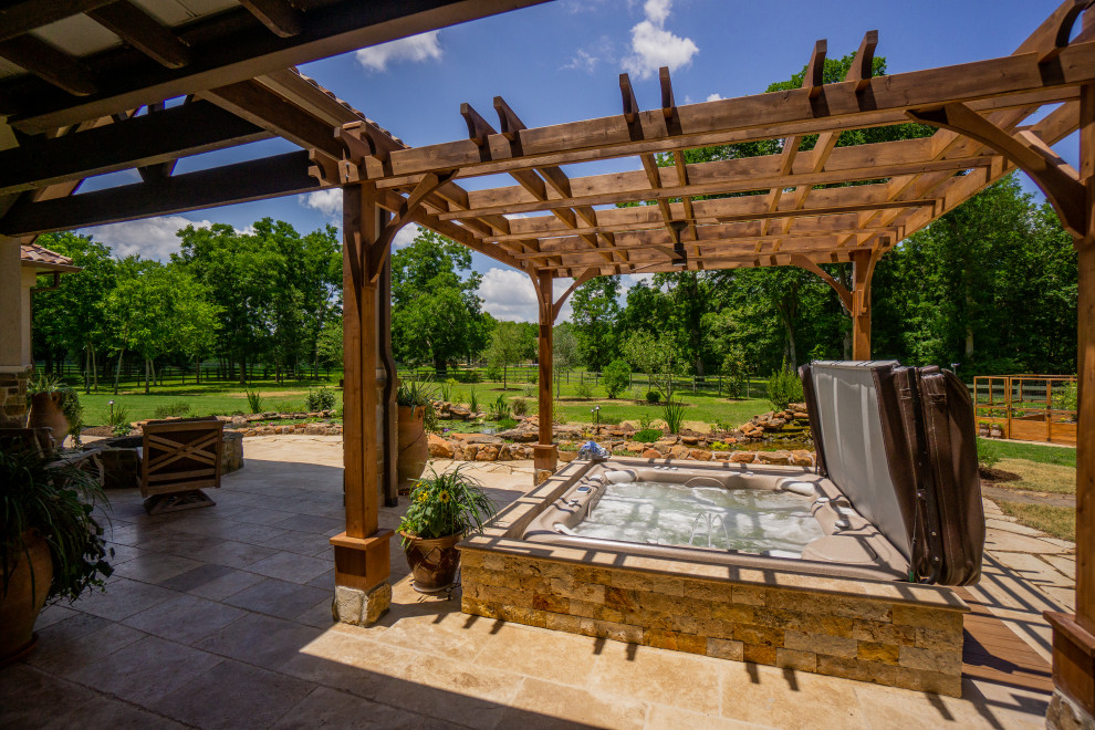 Photo of a small rustic back patio in Houston with natural stone paving and a pergola.