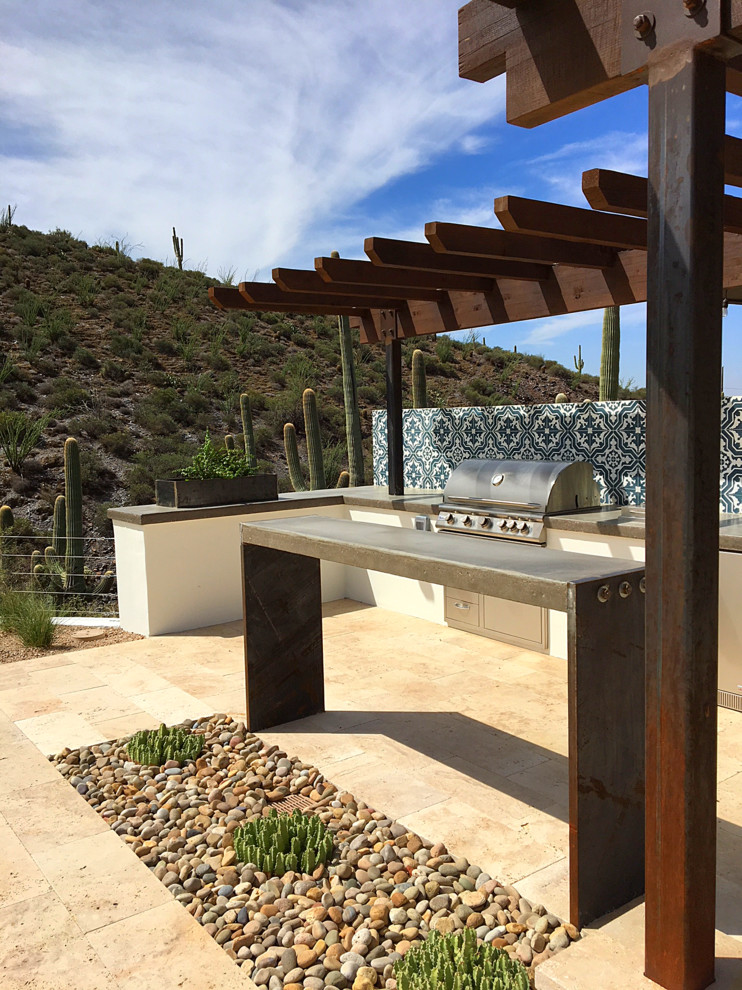 Photo of a large back patio in Phoenix with an outdoor kitchen, natural stone paving and a pergola.
