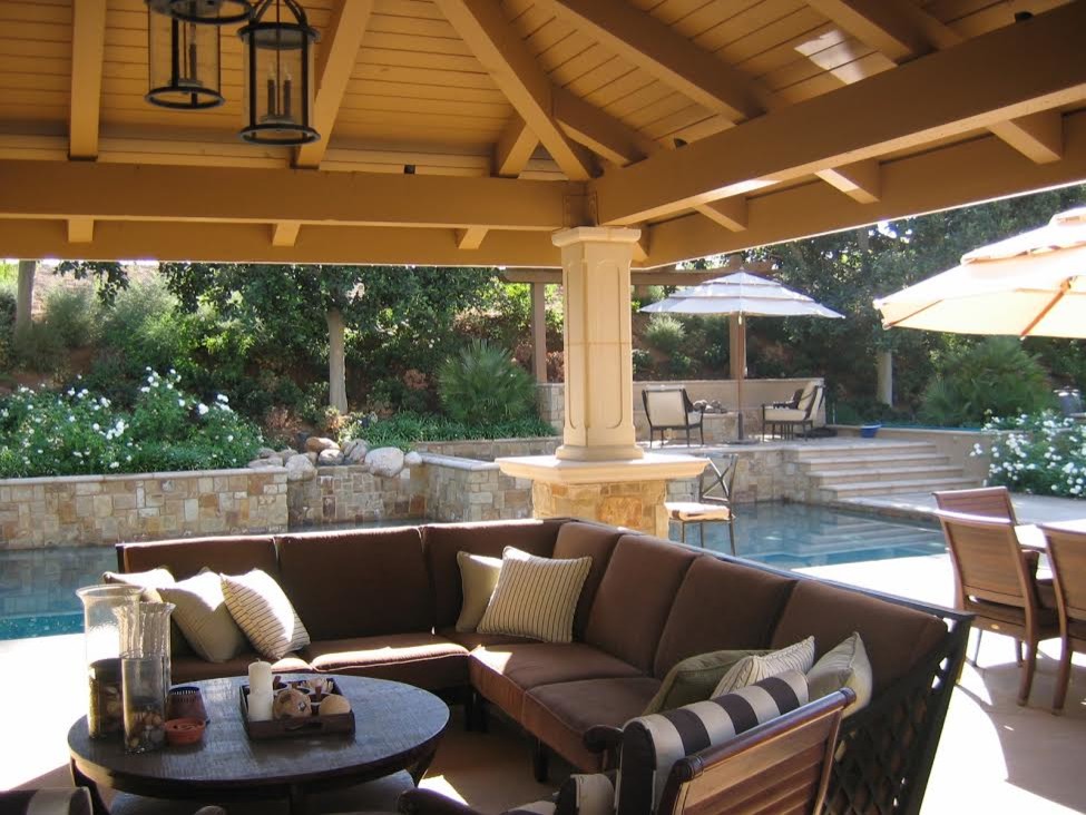 Exemple d'une grande terrasse arrière méditerranéenne avec une cuisine d'été, des pavés en pierre naturelle et une pergola.
