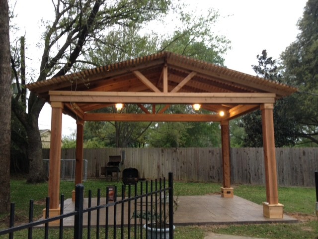 Example of a large mountain style backyard stamped concrete patio design in Houston with a pergola