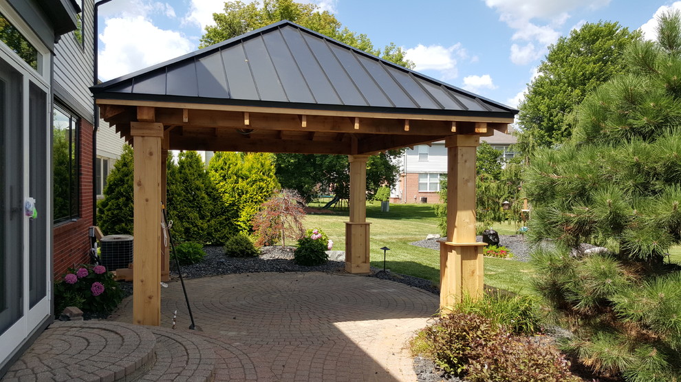 Immagine di un patio o portico minimalista di medie dimensioni e dietro casa con pavimentazioni in mattoni e un parasole