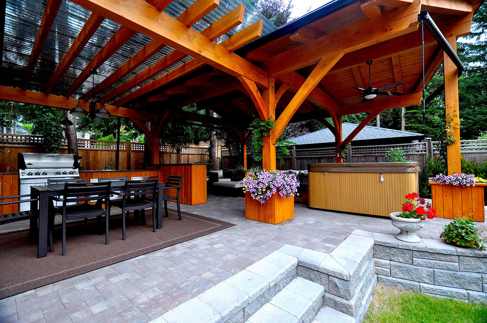 Idée de décoration pour une terrasse arrière minimaliste de taille moyenne avec une cuisine d'été, des pavés en pierre naturelle et un gazebo ou pavillon.