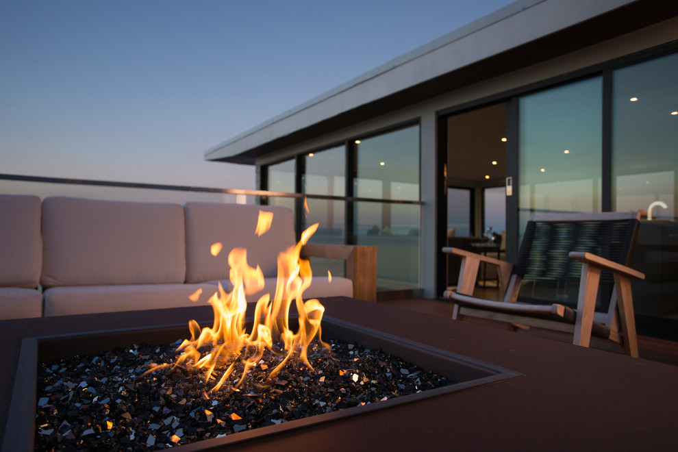 Cette image montre une terrasse arrière minimaliste avec un foyer extérieur.